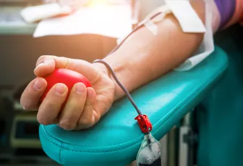 blood being drawn from an arm holding a red ball