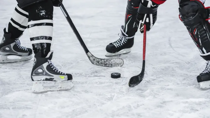 Two hockey players battle over the puck