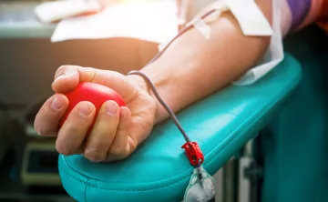 blood being drawn from an arm holding a red ball