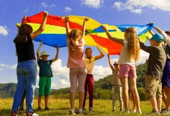 kids outside holding up a blaket