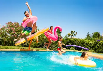 Kids jumping in a pool, summer bash pool party.