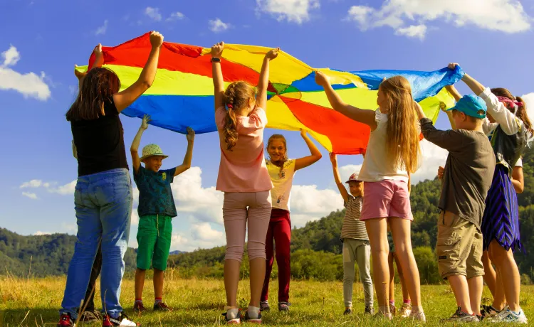 kids outside holding up a blaket