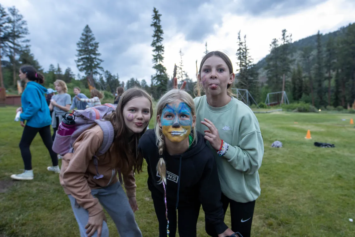 Three girls with face paint make faces into the camera.
